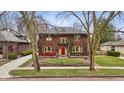 Beautiful two-story brick home with mature trees, manicured lawn, and charming architectural details at 43 W Hampton Dr, Indianapolis, IN 46208