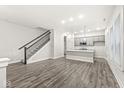 Bright, open-concept living space with gray wood floors and a staircase, adjacent to the kitchen at 537 Steinbeck Pl, Carmel, IN 46032