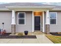 Attractive front entrance with a black door, white columns, and landscaping at 6433 Wasco Dr, Whitestown, IN 46075