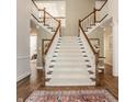 Elegant foyer featuring a grand staircase with white risers, wooden handrail, and hardwood floors at 7341 Washington Blvd, Indianapolis, IN 46240