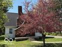 Charming home exterior featuring a brick chimney and blooming tree in a well-maintained lawn at 2029 W 60Th St, Indianapolis, IN 46228