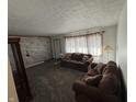 Living room featuring brown sofas, patterned curtains, and wood-look walls at 100 S Manhattan Ave, Muncie, IN 47303