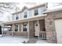 Inviting front porch with brick accents and a porch swing, leading to the front door during winter at 12643 Feldspar Rd, Indianapolis, IN 46236