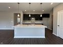 Stylish kitchen showcases an island with a sink, dark cabinets, white countertops, and modern pendant lighting at 450 Atlas Dr, Lebanon, IN 46052