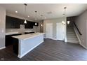Open-concept kitchen boasts dark cabinetry, quartz countertops, stainless steel appliances, and hardwood floors at 450 Atlas Dr, Lebanon, IN 46052