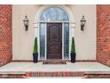 Close up of a dark wooden front door with decorative glass sidelights and sconces for added curb appeal at 6437 N Oxbow Way, Indianapolis, IN 46220
