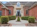 Stately brick home featuring manicured landscaping that leads to the arched front door and a statement window at 6437 N Oxbow Way, Indianapolis, IN 46220