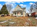A renovated craftsman home with a gray exterior, landscaped yard and a pink front door at 5704 E 16Th St, Indianapolis, IN 46218