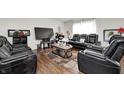 A luxurious living room featuring black leather reclining seating, hardwood floors, and stylish decor at 6623 Pasco Ln, Plainfield, IN 46168