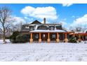 Charming log home featuring orange accents on the porch in a snow-covered setting at 1307 W 161St St, Westfield, IN 46074