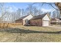 Side view of a brick home featuring a two-car garage and a spacious lawn at 851 Westridge Cir, Noblesville, IN 46062