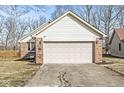 Attached two-car garage with white siding and brick accents with a concrete driveway at 851 Westridge Cir, Noblesville, IN 46062