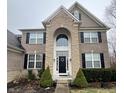 Close-up of the stately front entrance, showcasing the stone archway, black door, and decorative landscaping at 2504 Fawn Bluff Ct, Zionsville, IN 46077