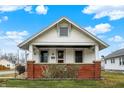Charming home featuring a cozy front porch with brick accents and lush greenery at 403 Colescott St, Shelbyville, IN 46176