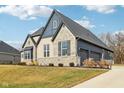 Charming brick home with a dark roof, professional landscaping, and a spacious three car garage at 5106 Zinnia Dr, Plainfield, IN 46168
