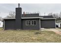 Rear view of the house shows gray siding, a chimney, and a small patio at 900 N Clarkdale Dr, Muncie, IN 47304