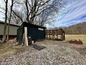 Backyard shed and chicken coop area with mature trees and gravel lot at 1072 S State Road 67, Martinsville, IN 46151