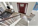 Bright foyer with hardwood floors, a staircase with white risers and wood railing, and a view of the front door at 11977 Cobblestone Dr, Fishers, IN 46037