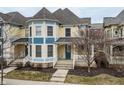 Attractive yellow townhouse with a quaint covered porch, surrounded by bare trees at 12755 Forsyth St, Carmel, IN 46032