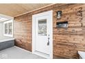 Close-up of the front porch featuring wood paneling, a white front door, and visible house numbers at 2421 E 11Th St, Indianapolis, IN 46201