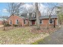 Well-kept red brick home with a black iron fence and mature trees surrounding the property at 4020 E 71St St, Indianapolis, IN 46220