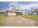 Brick home boasts an attached garage and long driveway, complemented by a spacious front lawn, mature trees, and inviting curb appeal at 511 Fall Creek Dr, Anderson, IN 46013