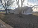 View of the front exterior featuring trees, gravel driveway, and light-colored siding at 1510 Josephine St, Martinsville, IN 46151