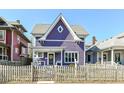 Quaint purple two-story home with a charming front porch and swing, set behind a picket fence at 66 N Ritter Ave, Indianapolis, IN 46219