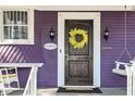 Charming front door with wreath, flanked by sconces, rocking chairs, and a porch swing at 66 N Ritter Ave, Indianapolis, IN 46219