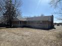 Back view of a one-story brick house with stone accents and an unfinished yard at 7114 E 10Th St, Indianapolis, IN 46219
