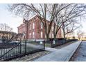 Brick building with wrought iron fence, mature trees, and street access at 714 Buchanan St # 17, Indianapolis, IN 46203