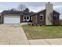 Charming brick home features an attached garage, a well-manicured lawn and concrete driveway at 971 Alexander St, Greenwood, IN 46143