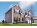 Lovely home featuring brick and siding exterior, well-kept lawn, mature trees, and an attached two car garage at 1006 Cherry Tree Ln, Greenwood, IN 46143