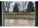 View from sliding glass doors to wooden back deck and large backyard with trees at 5746 Overcrest Dr, Indianapolis, IN 46237