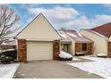 Delightful townhome boasting an attached garage and inviting entrance amid a serene, snow-dusted landscape at 6416 Friendship Cir, Indianapolis, IN 46268