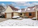 Inviting townhome featuring an attached garage and quaint outdoor seating area covered by recently fallen snow at 6416 Friendship Cir, Indianapolis, IN 46268