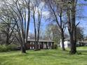 Traditional brick home surrounded by mature trees and a lush green lawn at 6632 Sargent Rd, Indianapolis, IN 46256