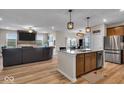 Open-concept living room and kitchen with hardwood floors, a granite island and modern appliances at 980 Cortland Ct, Westfield, IN 46074