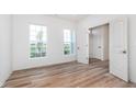 A bright bedroom with wood-look floors, neutral walls, two windows, and white doors at 1902 Blenker Dr, Carmel, IN 46032