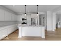 A modern kitchen featuring white cabinets, stainless steel appliances, and an island with pendant lighting at 567 Hidden Hills Dr, Pittsboro, IN 46167