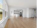 Open concept living room featuring light wood floors that flow into a white kitchen with stainless appliances at 567 Hidden Hills Dr, Pittsboro, IN 46167