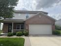 Charming two-story home with a brick facade, a two-car garage and covered front porch, enhanced by lush landscaping at 8048 Garden Ridge Rd, Indianapolis, IN 46237