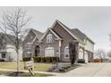 Beautiful two-story brick home featuring a manicured lawn, mature trees, and attached garage at 11478 Muirfield Trce, Fishers, IN 46037