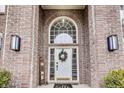 Close-up of a welcoming front door with a wreath, surrounded by brick and decorative details at 11478 Muirfield Trce, Fishers, IN 46037