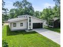 Modern home featuring a sleek design, dark garage door, striking windows, and a well-manicured lawn at 2689 Pearl St, Columbus, IN 47201