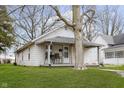 Cozy home featuring a charming front porch, green lawn, and mature tree at 3000 Pearl St, Anderson, IN 46016