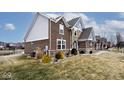 View of a two-story house with brick and stone accents and a well-maintained lawn, near a water feature at 3258 Cherokee Cir, Bargersville, IN 46106