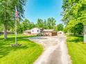 Spacious home with a gravel driveway, lush trees and an American flag at 6602 S 400 W, Columbus, IN 47201
