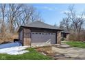 Close up of attached two car garage with brick facade, short driveway, and neat landscaping at 901 Detroit St, Beech Grove, IN 46107