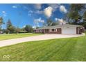 A lovely single-story brick home featuring an attached garage, manicured lawn, and extended driveway at 1002 Payton Ave, Indianapolis, IN 46219